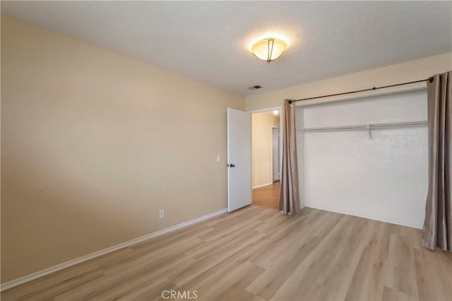 unfurnished bedroom with baseboards, visible vents, light wood finished floors, a closet, and a textured ceiling