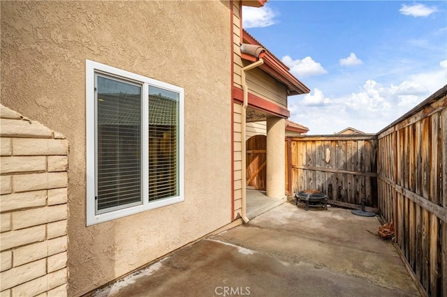 view of side of property with a patio, fence, and stucco siding