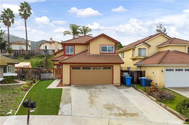 view of front of home featuring a tiled roof, concrete driveway, a front yard, and fence