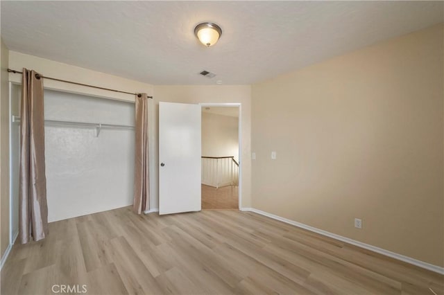 unfurnished bedroom with visible vents, baseboards, light wood-style floors, a closet, and a textured ceiling