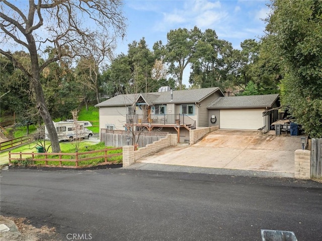 view of front of house featuring a fenced front yard, driveway, a wooden deck, and an attached garage