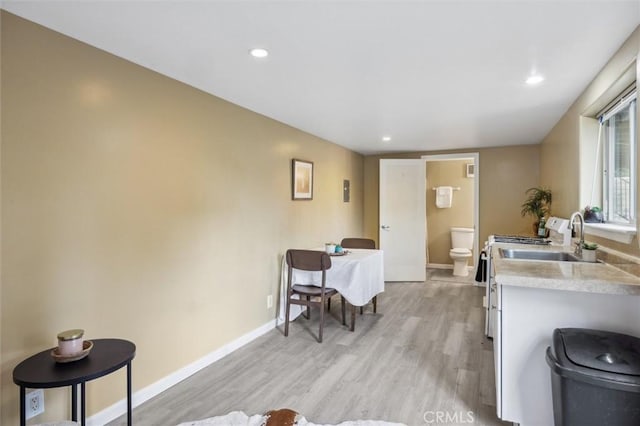 kitchen with light wood finished floors, light countertops, baseboards, and a sink