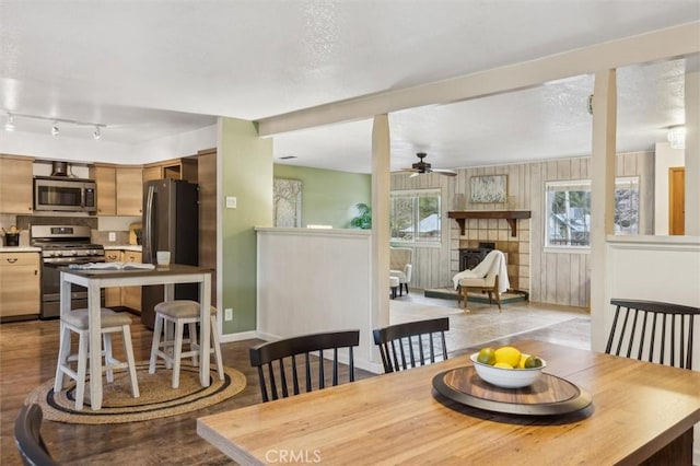 dining room featuring a wealth of natural light, a tile fireplace, baseboards, and ceiling fan