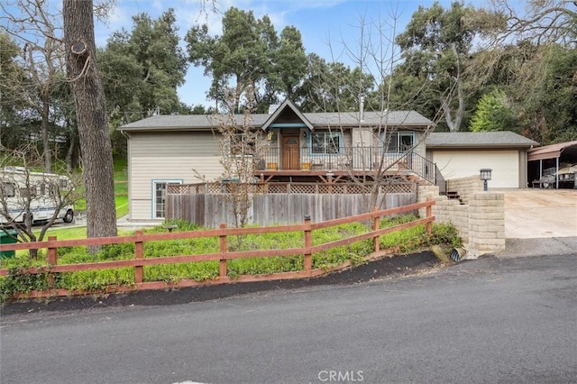 view of front facade with an outdoor structure, driveway, a garage, and a fenced front yard