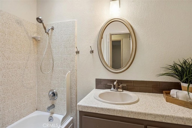 bathroom featuring vanity, a textured wall, and shower / bathtub combination