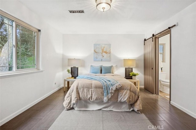 bedroom featuring a barn door, baseboards, visible vents, and wood finish floors