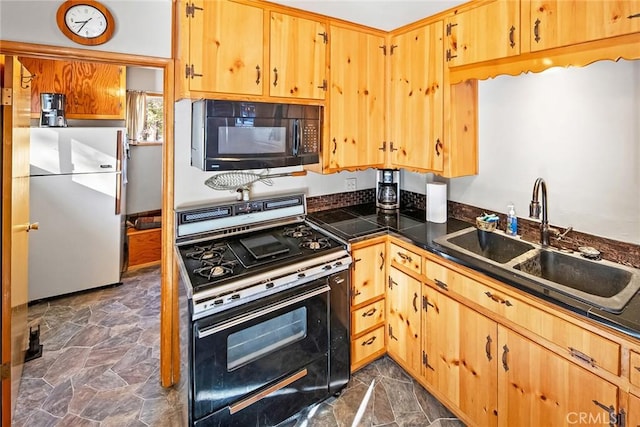 kitchen with freestanding refrigerator, a sink, black microwave, stone finish flooring, and range with gas cooktop