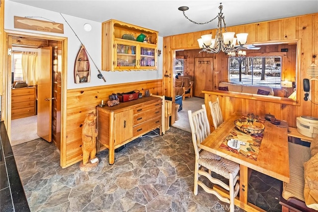 dining space with a notable chandelier, wooden walls, and stone flooring