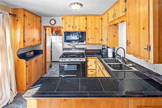 kitchen with freestanding refrigerator, a sink, gas range oven, black microwave, and dark countertops