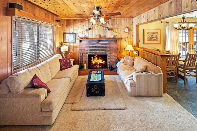 living room with a brick fireplace, wood ceiling, wood walls, and ceiling fan with notable chandelier