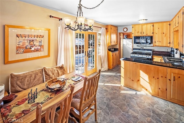 kitchen with a notable chandelier, dark countertops, freestanding refrigerator, stainless steel range with gas cooktop, and black microwave