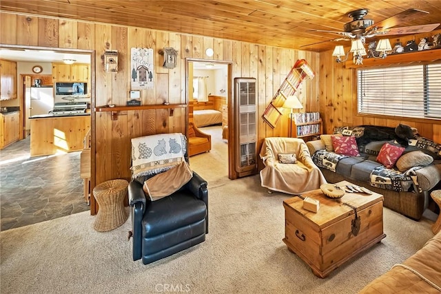 carpeted living room with wood walls, wooden ceiling, and ceiling fan