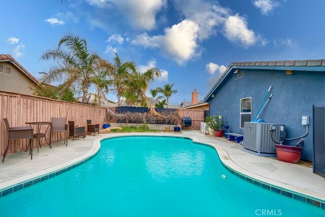 view of swimming pool with a patio, central air condition unit, a fenced backyard, and a fenced in pool