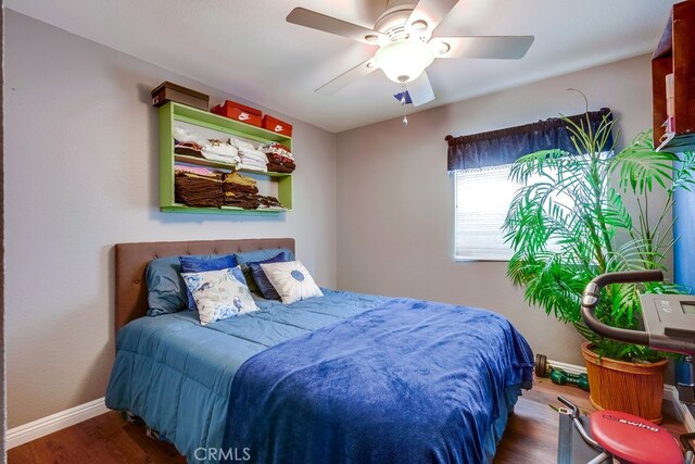 bedroom featuring ceiling fan, baseboards, and wood finished floors