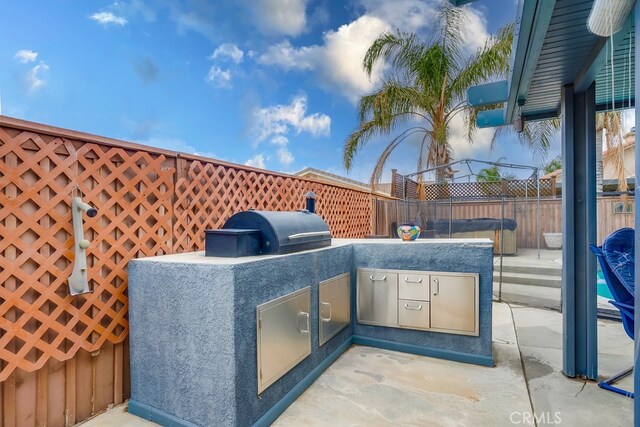 view of patio featuring a fenced backyard, area for grilling, and an outdoor kitchen
