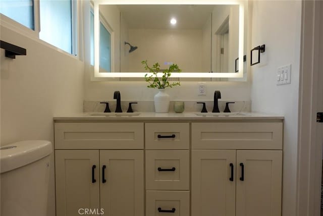 bathroom featuring a sink, toilet, and double vanity