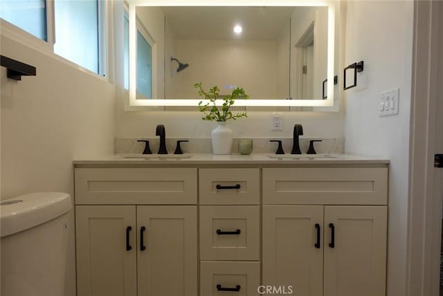 full bath with toilet, a sink, and double vanity