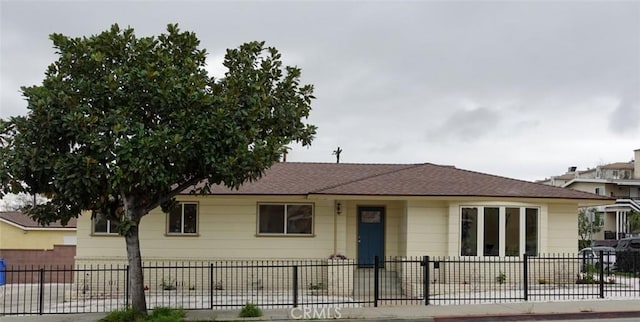 view of front of property featuring a fenced front yard and roof with shingles