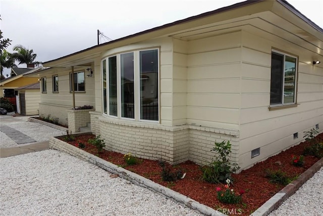 view of home's exterior with crawl space and brick siding