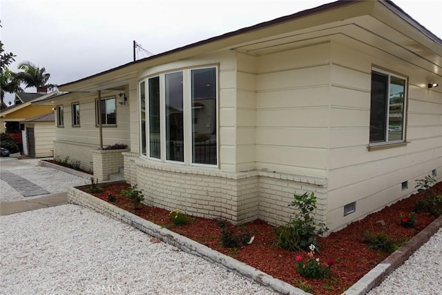 view of side of property with crawl space and brick siding