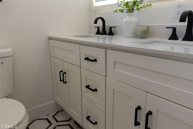 bathroom featuring double vanity, toilet, and a sink