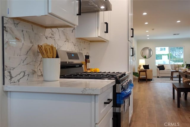 kitchen with white cabinets, recessed lighting, under cabinet range hood, stainless steel gas stove, and light wood-style floors