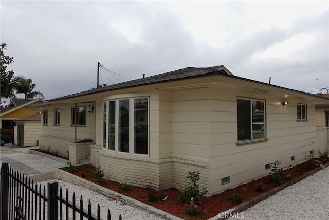 view of home's exterior with crawl space, brick siding, and fence