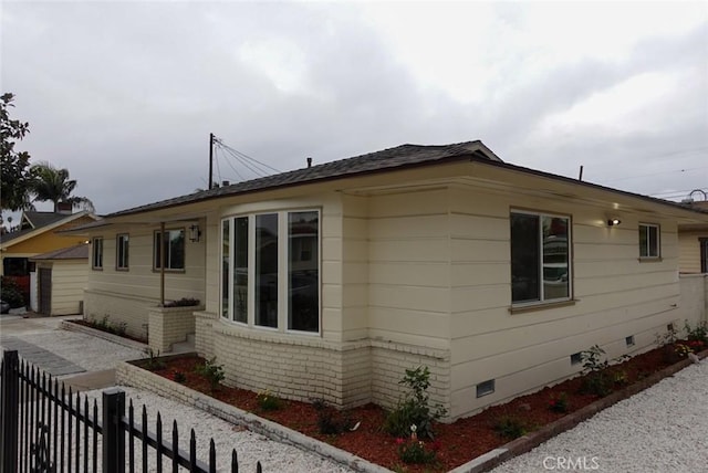 view of home's exterior with fence, crawl space, and brick siding