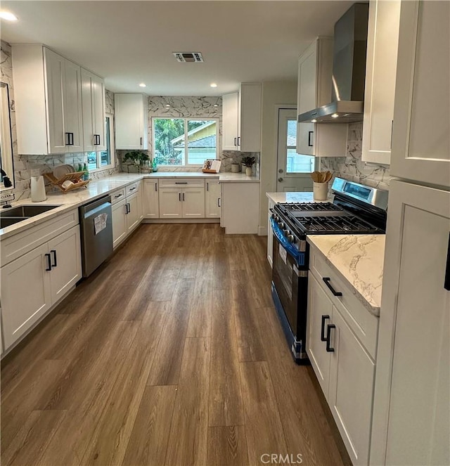 kitchen featuring dark wood-style flooring, visible vents, backsplash, wall chimney range hood, and appliances with stainless steel finishes