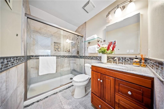 bathroom with visible vents, toilet, a stall shower, tile walls, and vanity