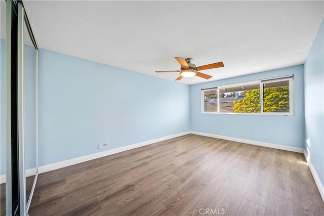 unfurnished room featuring a ceiling fan, wood finished floors, and baseboards