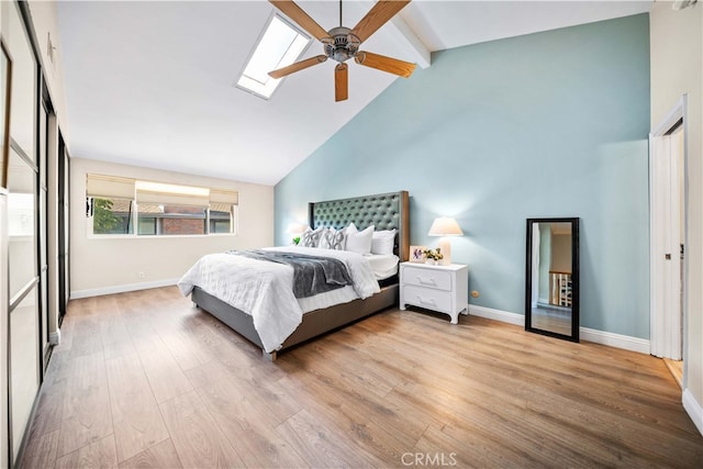 bedroom with baseboards, high vaulted ceiling, beam ceiling, a skylight, and light wood-type flooring