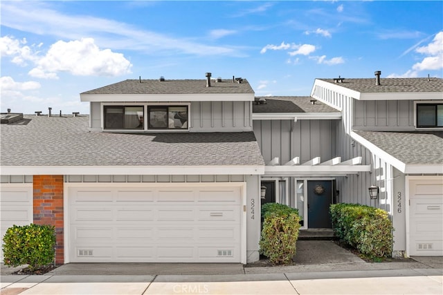 townhome / multi-family property featuring board and batten siding, a shingled roof, and driveway