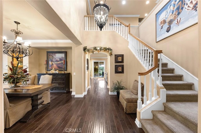 entryway featuring stairway, baseboards, ornamental molding, dark wood-type flooring, and a chandelier