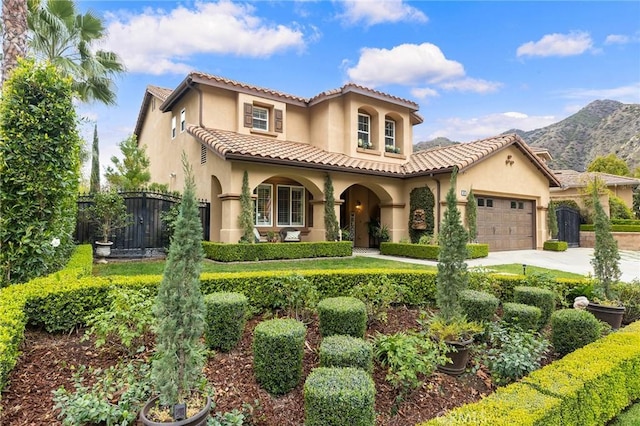 mediterranean / spanish-style home featuring stucco siding, fence, concrete driveway, and a tiled roof