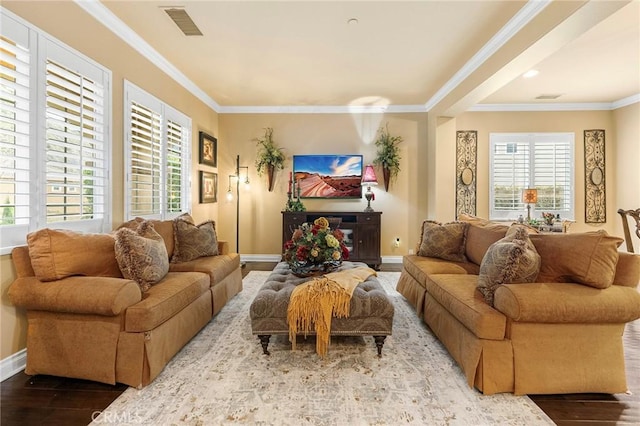 living room with baseboards, wood finished floors, visible vents, and ornamental molding