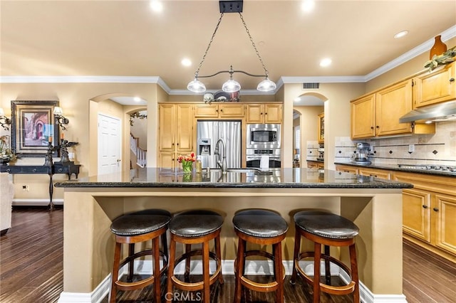 kitchen featuring a sink, arched walkways, under cabinet range hood, and stainless steel appliances