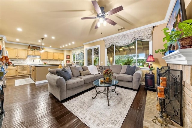 living area featuring dark wood-style floors, crown molding, and a ceiling fan