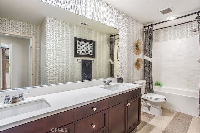 bathroom featuring toilet, wallpapered walls, a sink, and visible vents