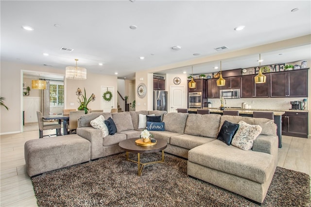 living room featuring light wood finished floors, recessed lighting, and stairway