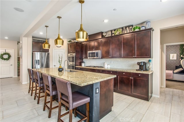kitchen with a kitchen breakfast bar, tasteful backsplash, a sink, appliances with stainless steel finishes, and light stone countertops