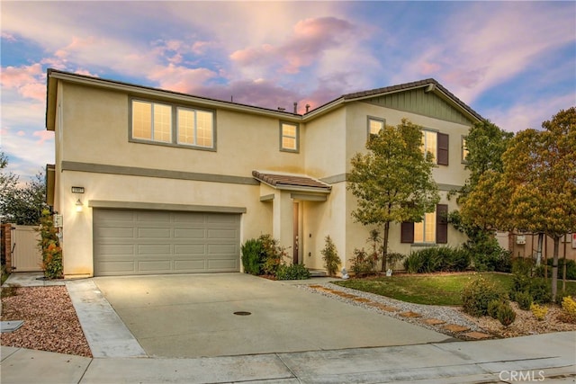 traditional-style house with concrete driveway, an attached garage, and stucco siding