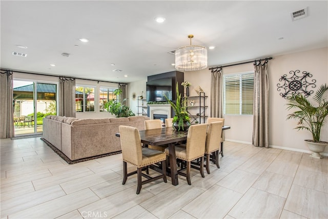 dining area with a chandelier, a glass covered fireplace, visible vents, and recessed lighting