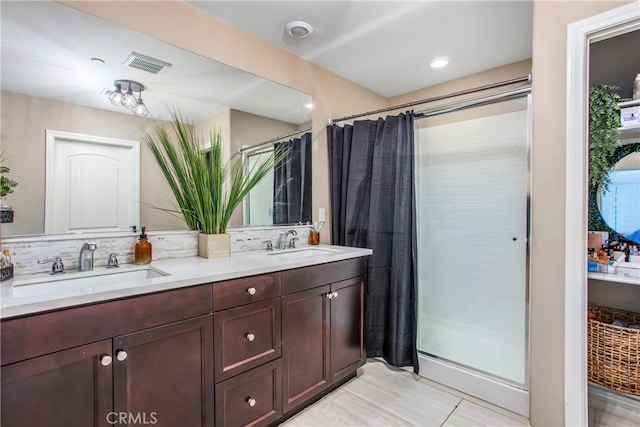 bathroom with a tile shower, a sink, visible vents, and double vanity