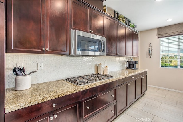 kitchen featuring light stone countertops, decorative backsplash, baseboards, and stainless steel appliances