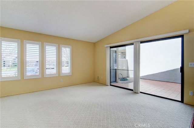 spare room featuring carpet flooring, lofted ceiling, and plenty of natural light