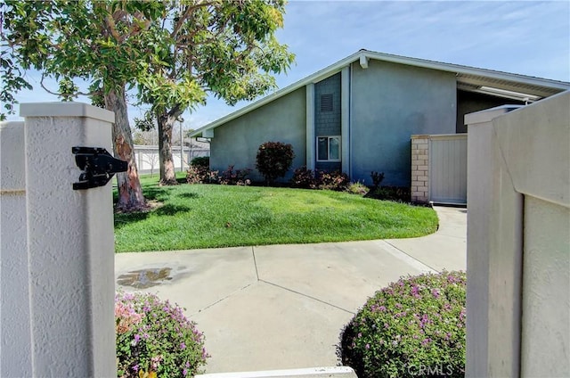 view of property exterior featuring stucco siding, a yard, and fence