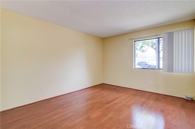 unfurnished room with light wood-type flooring and a textured ceiling