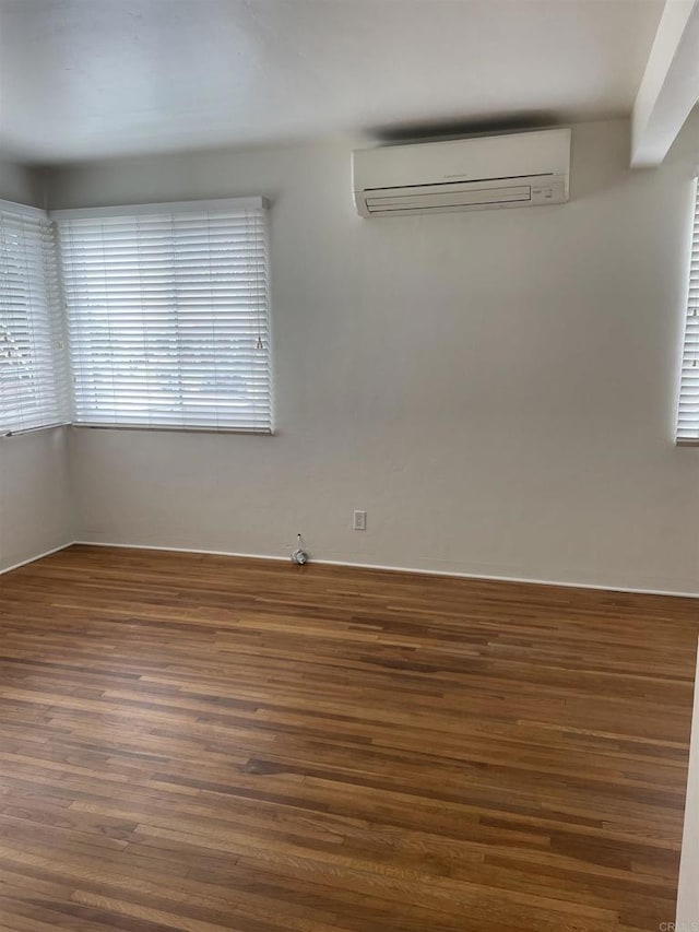 unfurnished room with a wall unit AC and dark wood-style flooring