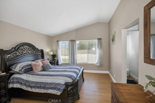 bedroom featuring baseboards, lofted ceiling, and wood finished floors